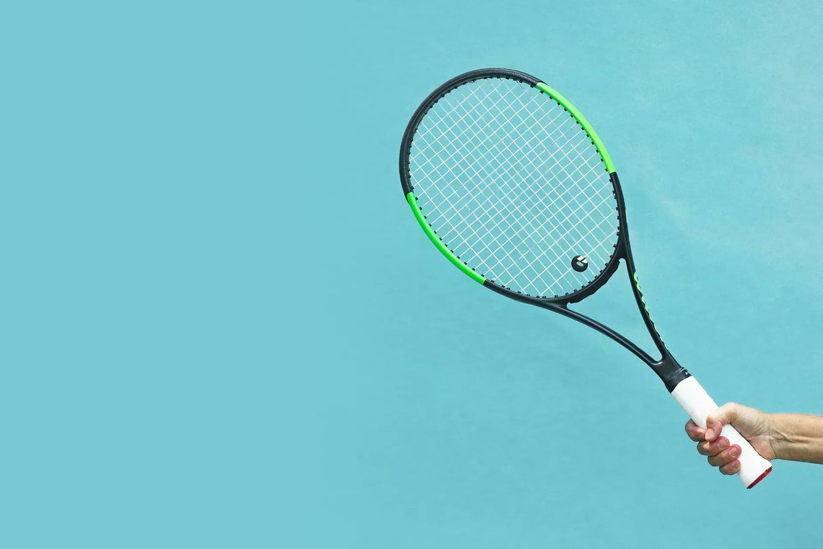 Neuroathletik im Tennis: Eine Hand hält einen Tennisschläger auf blauem Grund