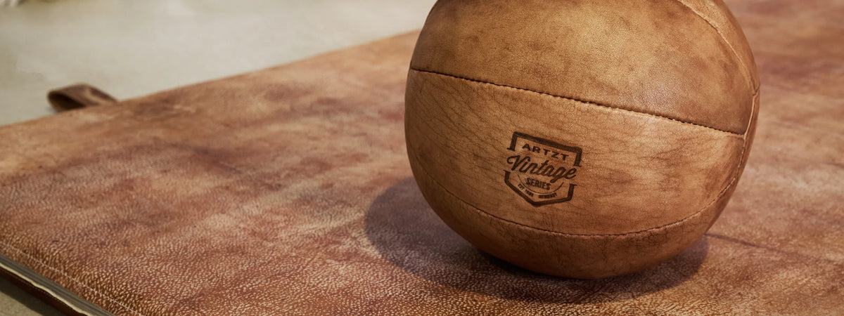 Ein ARTZT Vintage Series Medizinball liegt auf einer brauen Ledermatte.
