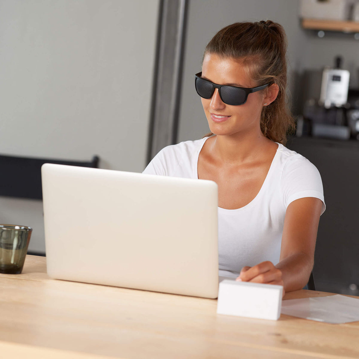 Eine Frau sitzt am Schreibtisch vor einem Laptop und trägt eine ARTZT neuro Rasterbrille.