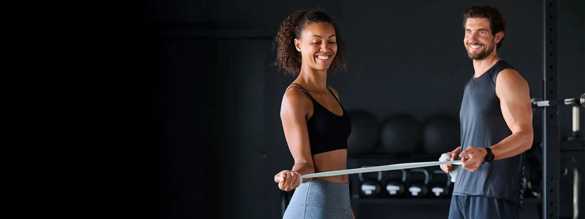 Startseite des Onlineshops guseibe.com: Eine Frau und ein Mann trainieren in einem Fitnessraum mit einem grauen Fitnessband.