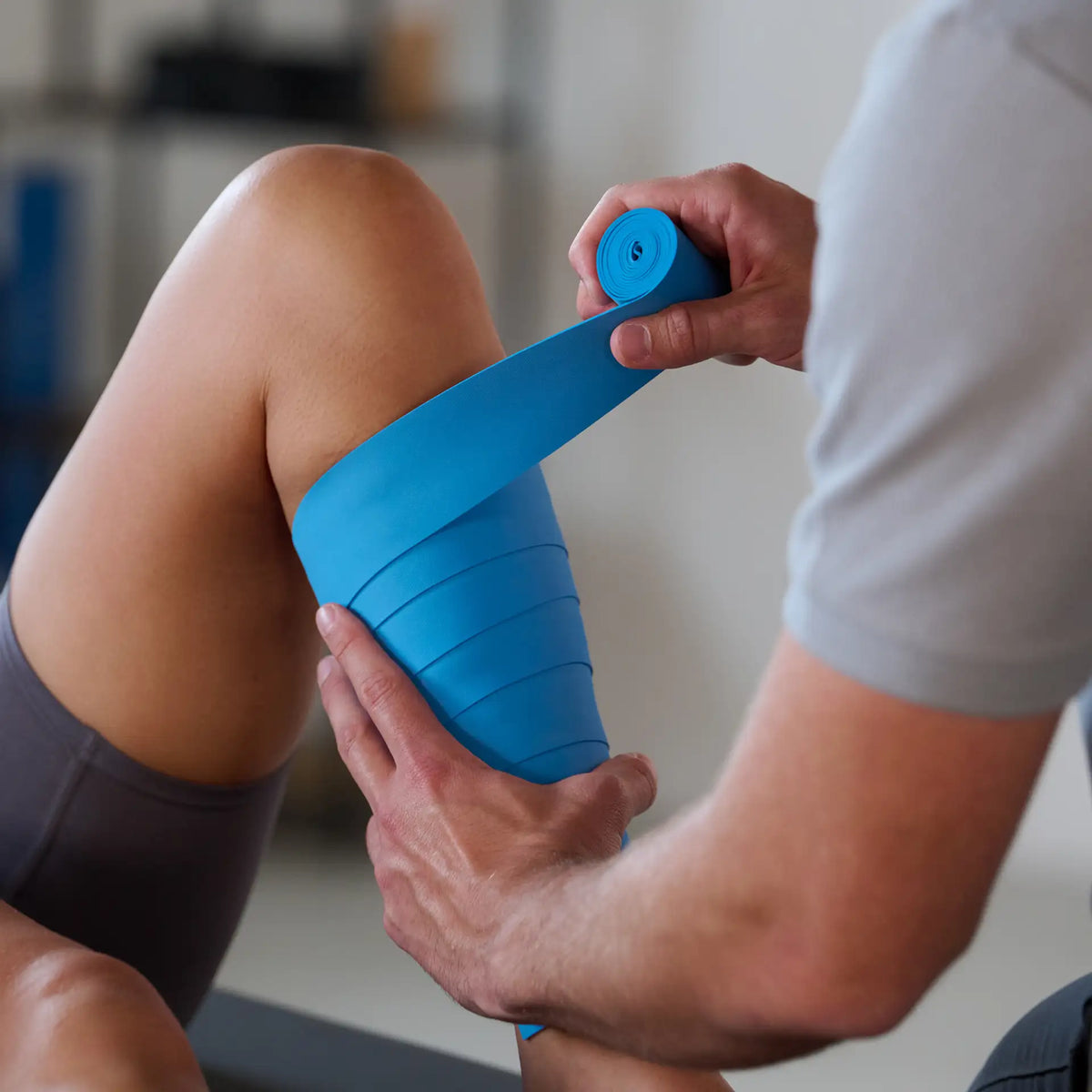 Therapeut legt ein ARTZT thepro Flossband um die Wade einer Patientin zur Anwendung im Training an. #länge_3 m