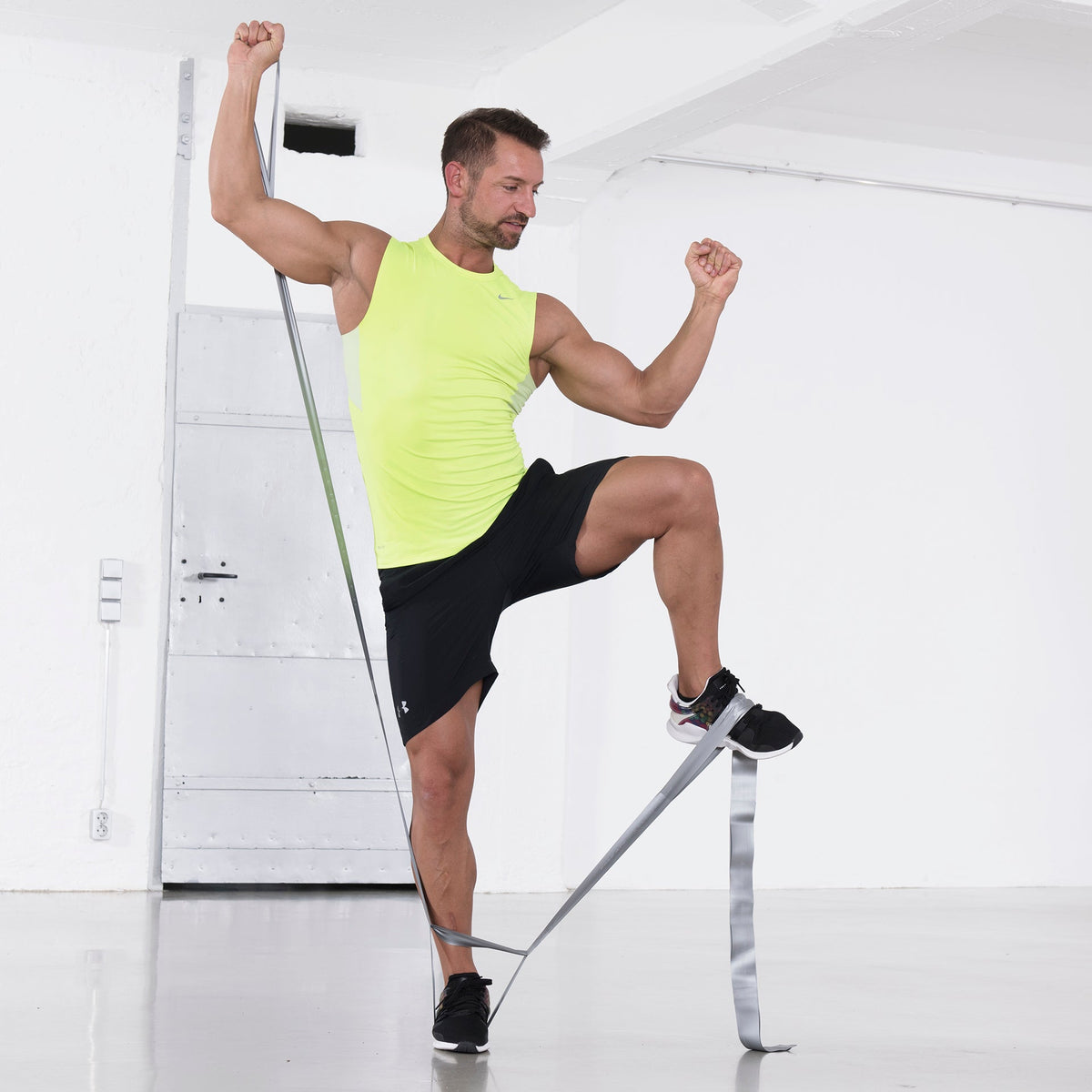 Mann macht Ganzkörpertraining mit einem silbernen TheraBand CLX